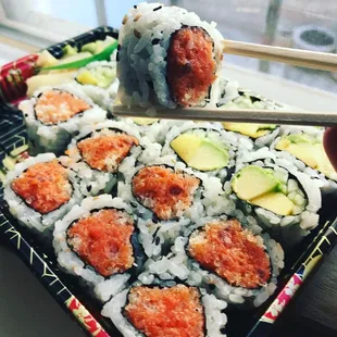 a person holding chopsticks over a plate of sushi