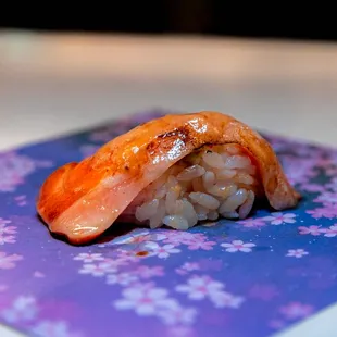 a piece of sushi on a purple and blue background