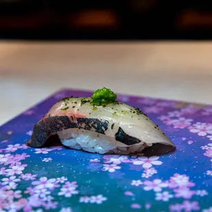 a piece of sushi on a purple and blue plate