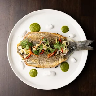 a fish with vegetables on a white plate