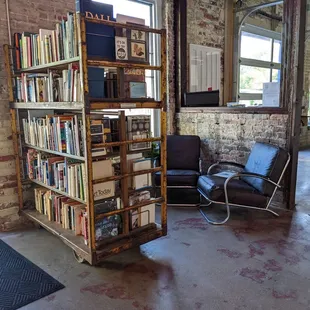 a bookshelf and a chair in a room with exposed brick walls