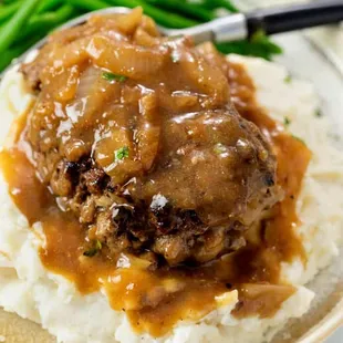 a plate of mashed meatballs with gravy and green beans