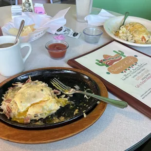 Pierre's Special w/ham + green chili sauce served in a sizzling skillet, a smothered burrito w/sausage and green chili sauce + hash browns.