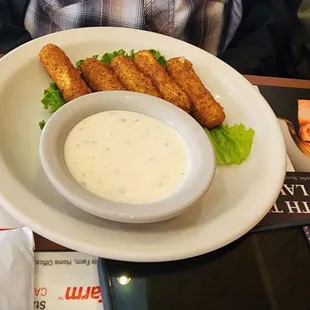 a plate of fish fingers and a bowl of dip