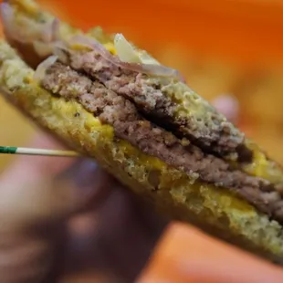 a hand holding a sandwich with a toothpick in it