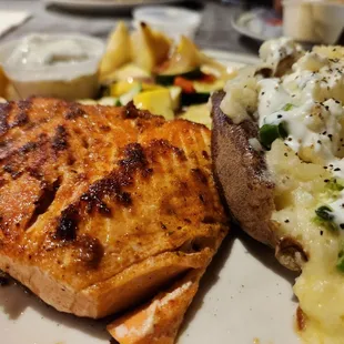 a plate of food that includes fish, potatoes, and a salad