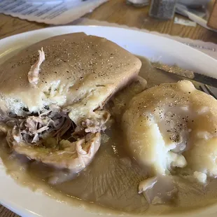 Shredded pork sandwich smothered in gravy with mashed potatoes