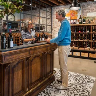 a man and a woman standing at a wine bar