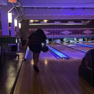 a woman walking down a bowling alley