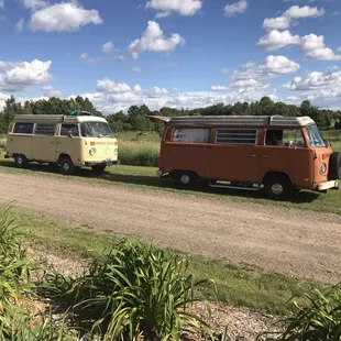 three vw vans parked on a dirt road