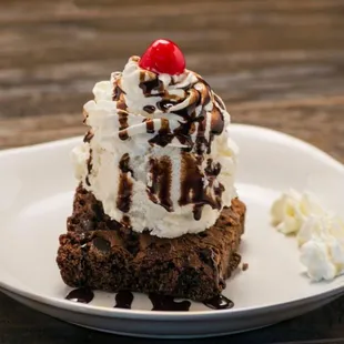 a piece of brownie topped with whipped cream and a cherry