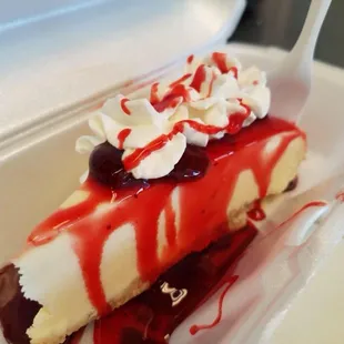 a slice of cheesecake with cherry sauce and whipped cream