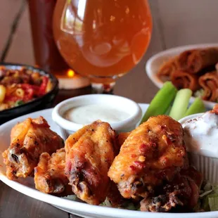 a plate of chicken wings, a salad, and a glass of beer