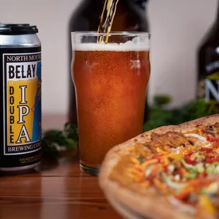 a beer being poured over a pizza