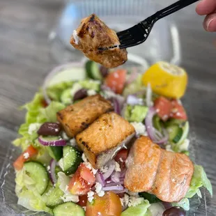 a hand holding a fork over a salad