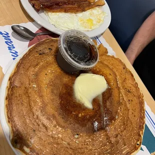 Single blueberry pancake with eggs and bacon