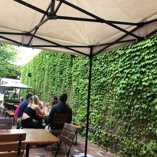 people sitting at tables under an umbrella