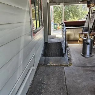 Front door entrance off a covered patio area with some outdoor seating (to the right)