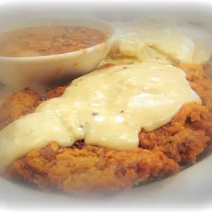a plate of fried chicken with gravy and mashed potatoes