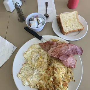 a plate of eggs, bacon, hash browns and toast