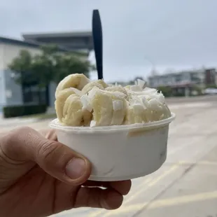 a hand holding a bowl of ice cream