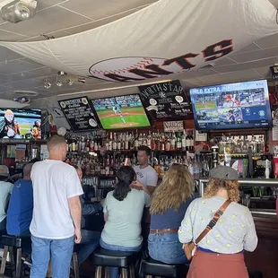 people sitting at the bar watching a baseball game