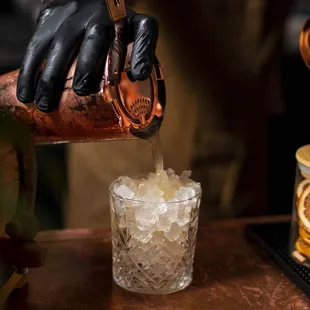 a person pouring a drink into a glass