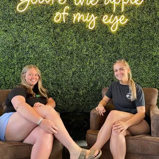 two women sitting in chairs in front of a wall with the words you're the apple of my eye