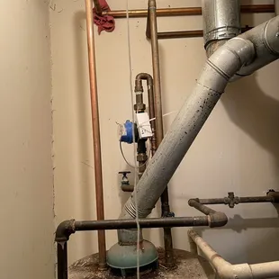 Rag holding pipe away from wall, dirt on water heater, and water damage on ceiling.