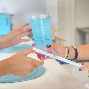 two hands holding a toothbrush and a cup of water