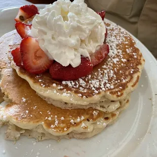 Pancakes with strawberries and whip cream topping.