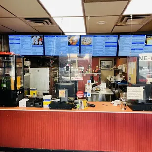 a restaurant counter with menus on the wall