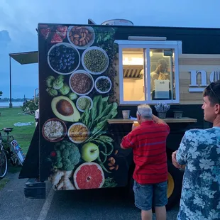two people standing in front of a food truck