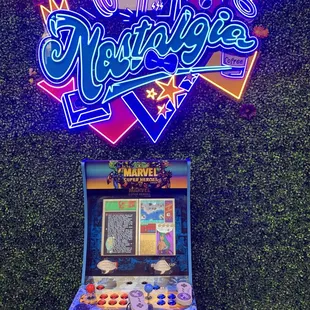 a pinball machine in front of a neon sign
