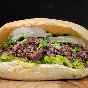 a beef sandwich with lettuce and onions