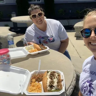 Two gals loving their Philly cheesesteak sandwich lunches!