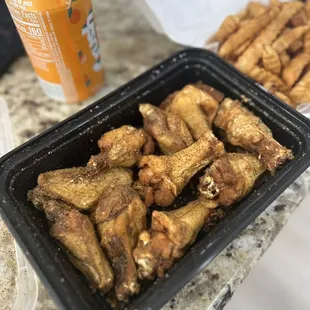 a can of soda and a tray of chicken wings