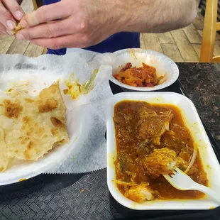 Fish, chicken (round bowl), and mostly eaten up paratha.