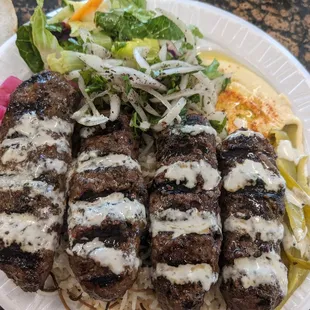 Lamb Kafta Kabob plate with lamb seasoned with middle eastern seasoning, rice, salad, hummus, tahini sauce and pickles