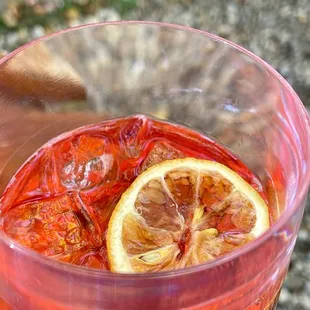 a glass of red liquid with lemon slices in it