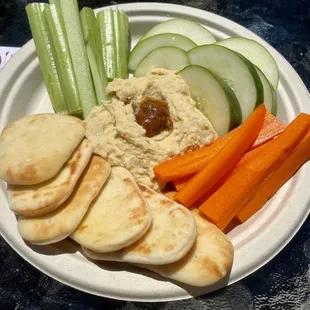 a plate of hummus, carrots, celery, and crackers