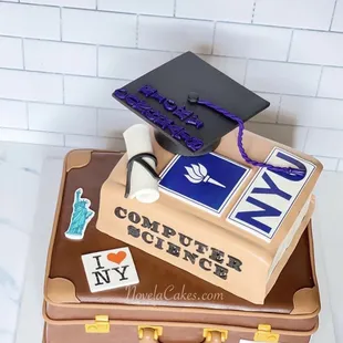 a book, graduation cap, and diploma on top of a suitcase
