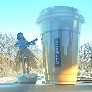 a statue of a hula girl playing a guitar next to a cup of coffee