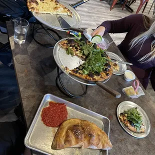 a woman serving a variety of pizzas