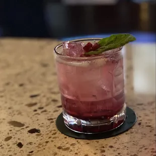 a pink cocktail with a mint leaf garnish