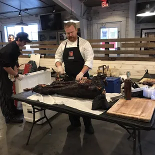 two chefs preparing a large piece of meat