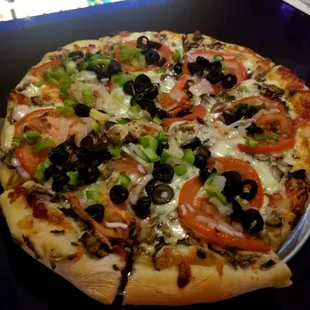 a pizza with tomatoes, olives, and peppers