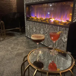 two people sitting in front of a fireplace