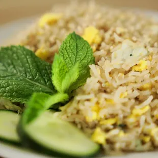 a plate of fried rice with cucumber and mint