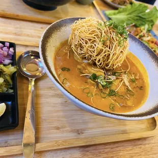 Khai soi street food with both fresh &amp; crispy noodles , pickled veggies in a curry broth